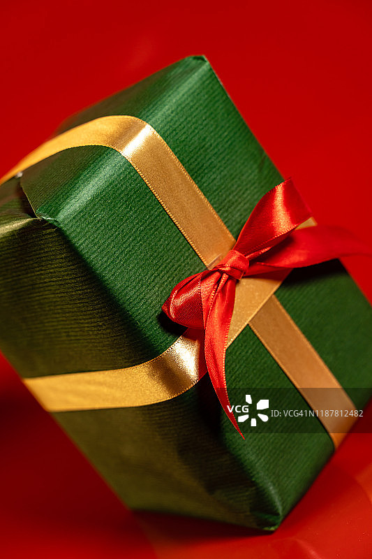 绿色的圣诞礼物与红丝带在红色的背景图片素材