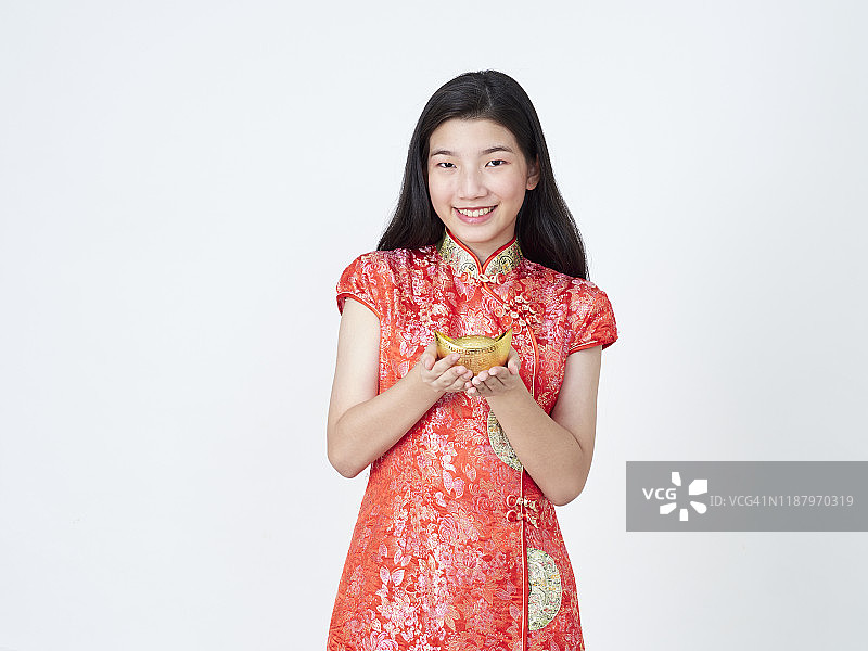 2020年中国新年。身着中国传统旗袍的年轻女子手持白色背景上的中国黄金图片素材