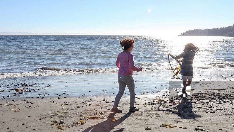 年轻女孩在海滩上玩水藻图片素材