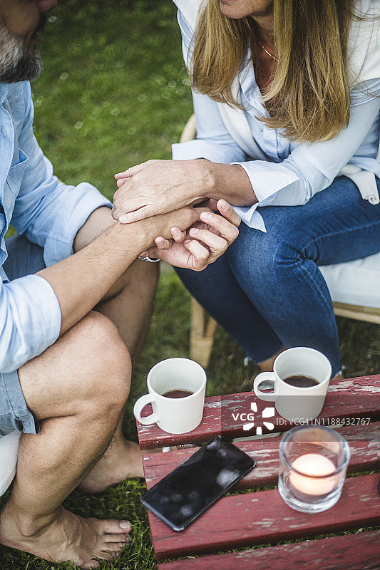 高角度的成熟夫妇牵手而坐在后院期间的咖啡时间图片素材