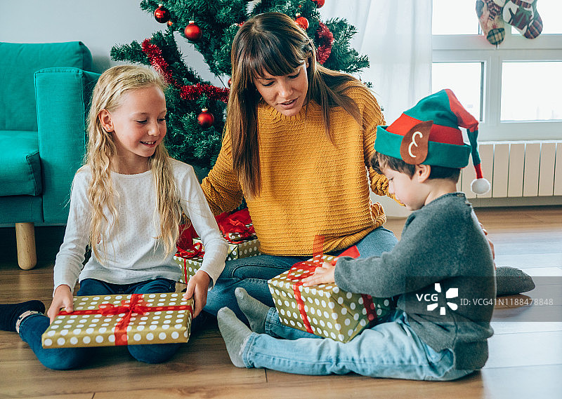一家人在圣诞树旁打开礼物图片素材