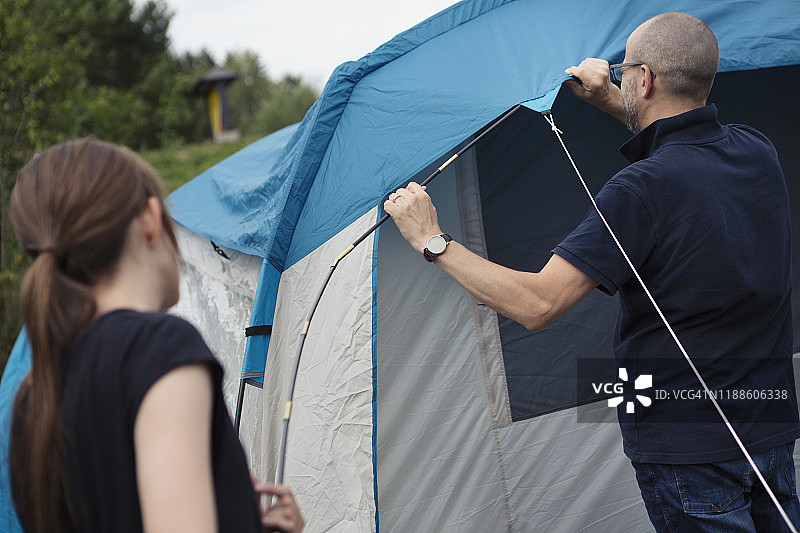 一个十几岁的女孩在营地帮助父亲组装家庭帐篷图片素材