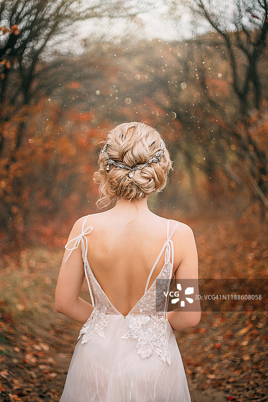 神秘的，美丽的年轻女子穿着白色的裙子与开放的后背。新娘的发型图片素材