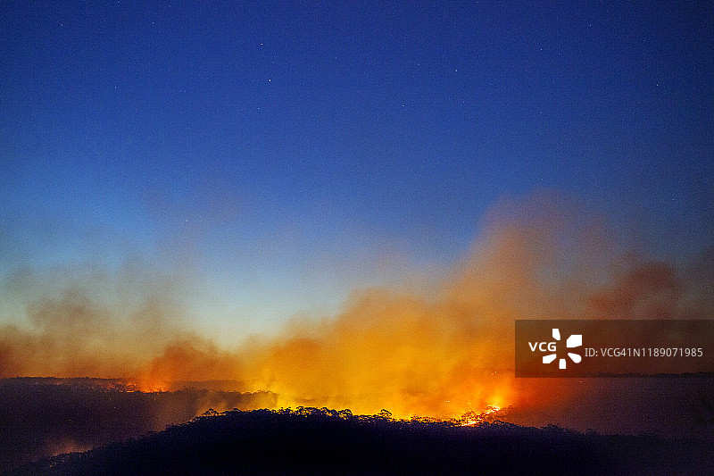森林火灾，山火与火焰照亮烟云和蓝色的黄昏天空，蓝山，澳大利亚图片素材