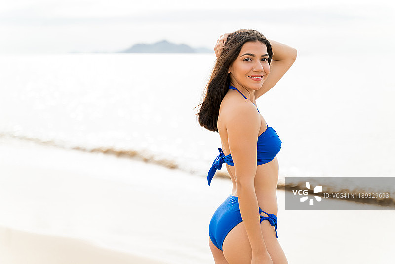 在海滩上穿着蓝色泳装的自信女人图片素材