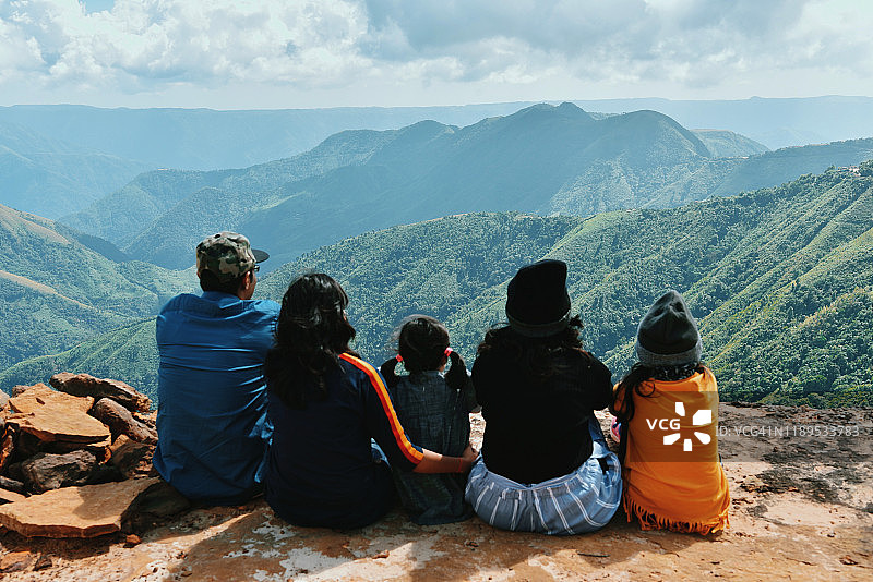 家人坐在悬崖上看山谷景色图片素材