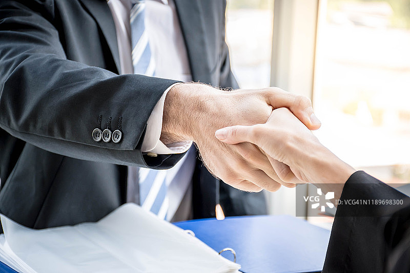 一男一女在办公室里握手表示合作。老板与求职者握手表示欢迎。握手确认合伙关系。图片素材