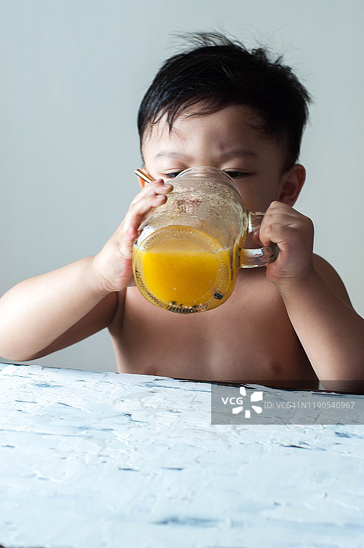 一个亚洲男孩正在喝黄色的西瓜奶昔图片素材