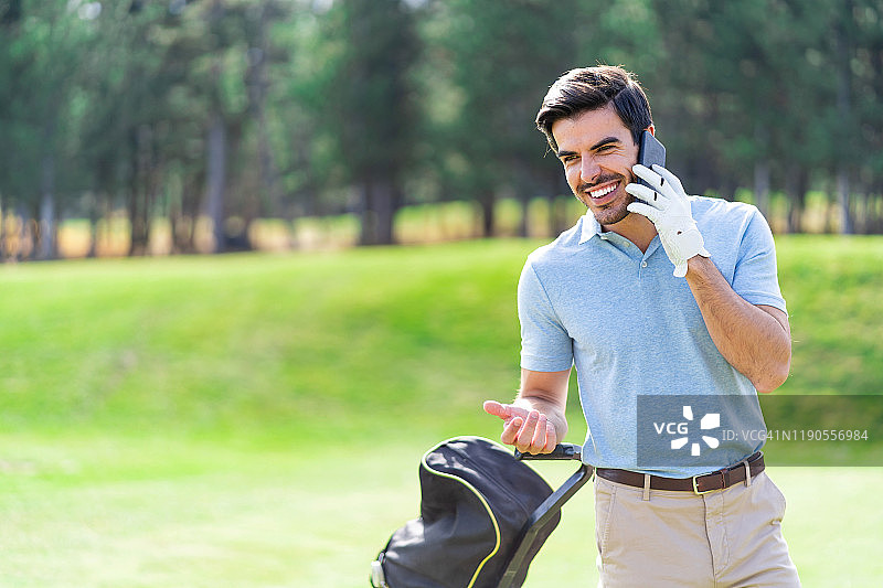 男性高尔夫球手站在高尔夫球场上，用智能手机打电话图片素材