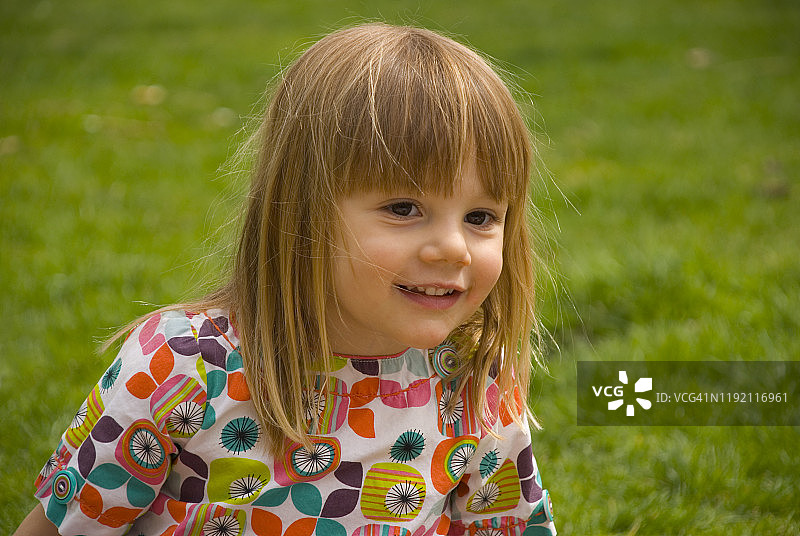 年轻女孩坐在草地上微笑图片素材