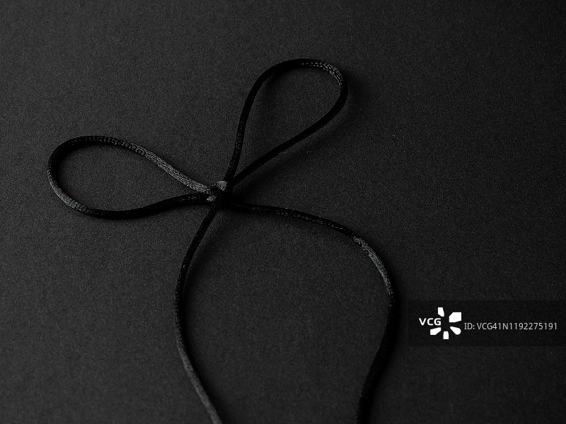 明亮的黑色丝线蝴蝶结在一个黑色的背景图片素材