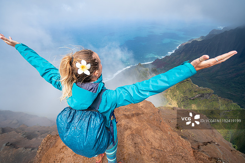 年轻的女子站在山顶上，俯瞰着张开双臂的大海，美国夏威夷图片素材