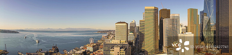 白天的西雅图全景，办公大楼和摩天大楼与摩天轮，普吉特湾，到达渡轮，商业滨水和奥林匹克山在远处。图片素材