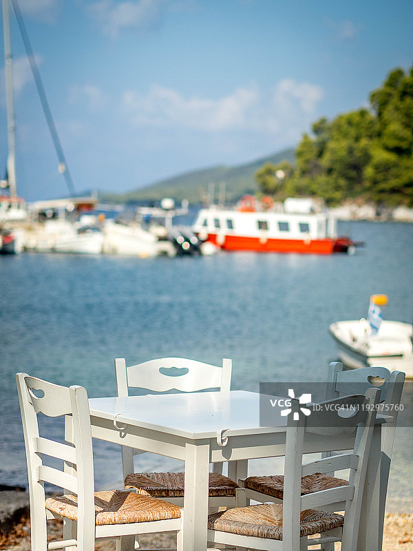 一张椅子和一张桌子的特写，在海滨，斯塔菲洛斯海滩，斯科佩洛斯，希腊图片素材