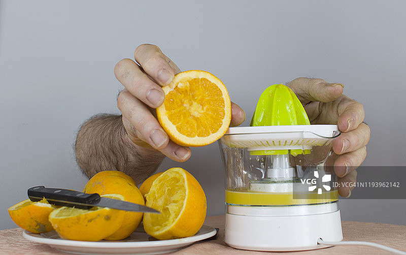 男人用榨汁机榨橙子图片素材