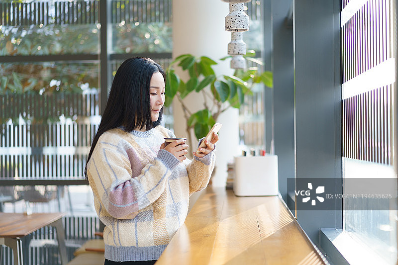 年轻的亚洲女性使用智能手机与咖啡馆图片素材