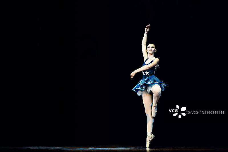 年轻女孩在黑暗的舞台上跳芭蕾舞图片素材