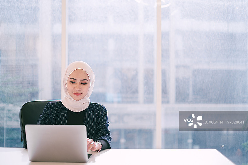 年轻的穆斯林女商人使用笔记本电脑的肖像图片素材