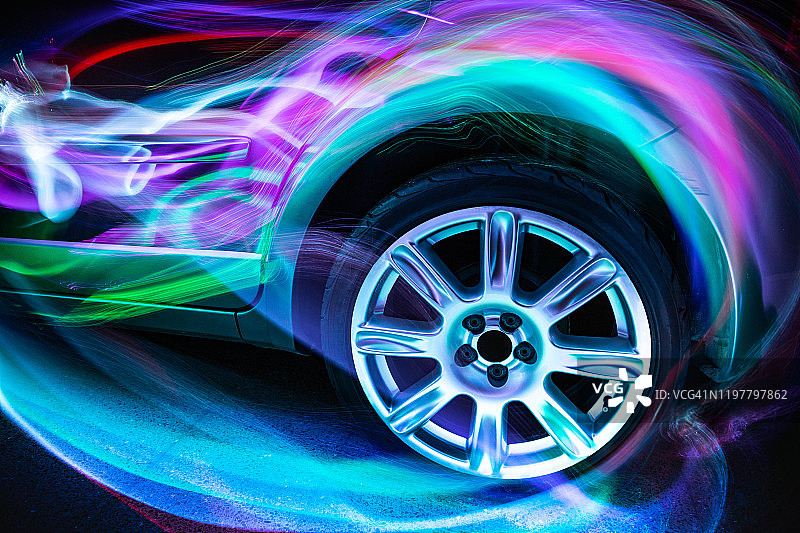 在夜晚，五颜六色的空气动力学灯光轨迹与汽车形状嬉戏。图片素材