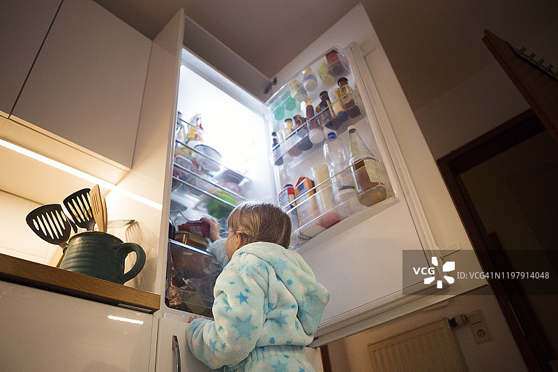 孩子(6-7岁)晚上看着冰箱里的食物图片素材