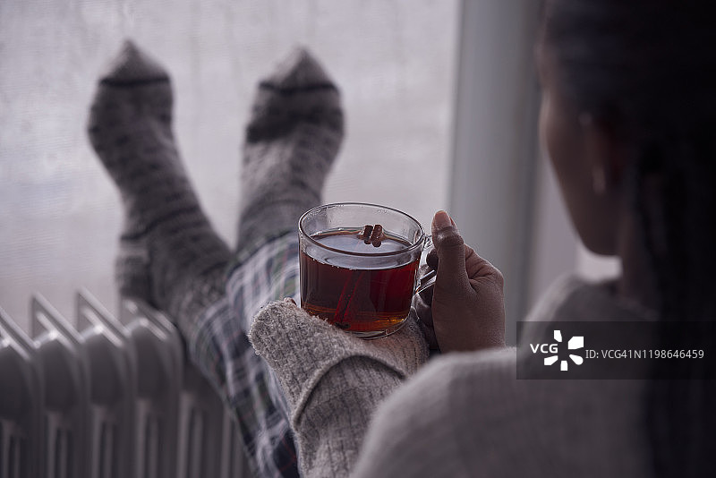 后面是一个女人在阴冷潮湿的天气在家喝茶的画面。图片素材
