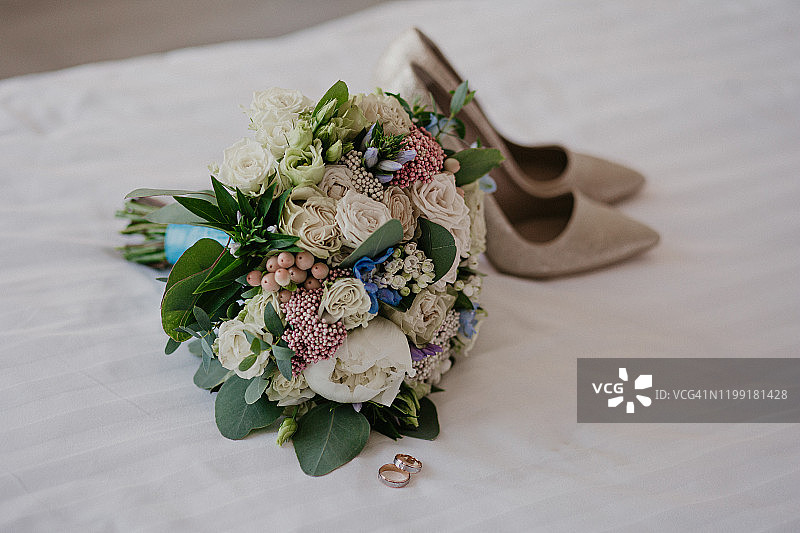 给新娘的饰品:戒指、鞋子、婚礼花束和香水。早上的新娘。婚礼的细节图片素材