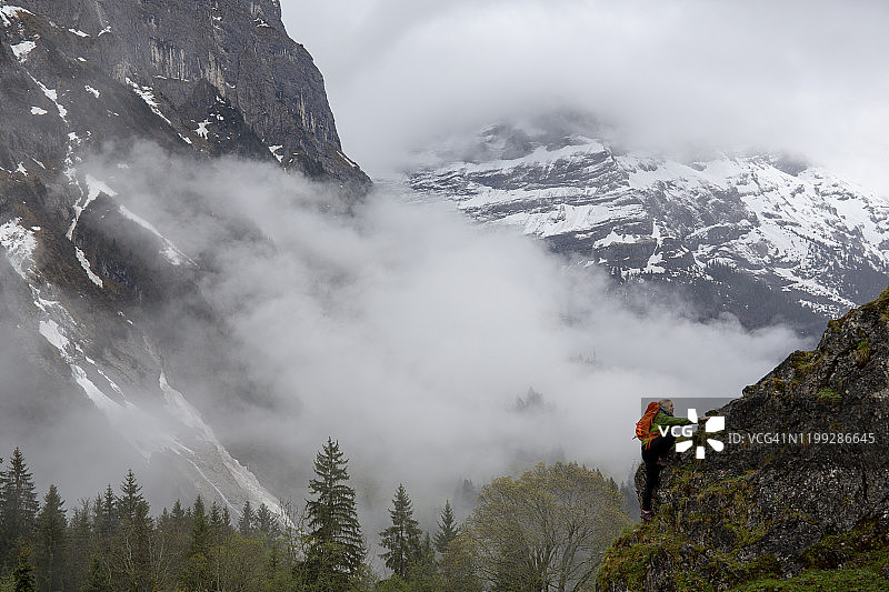 女性徒步旅行者背着背包攀登岩石山脊图片素材