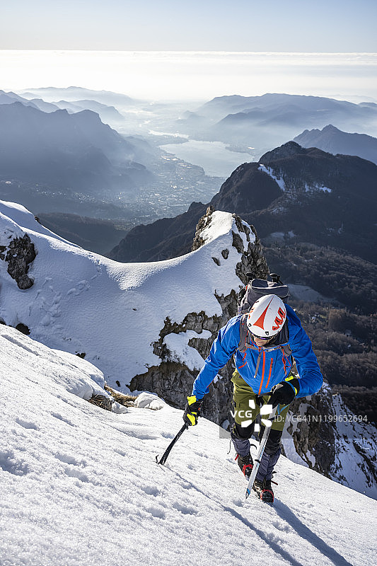 意大利莱科，一名登山运动员正在攀登一座白雪皑皑的山峰图片素材