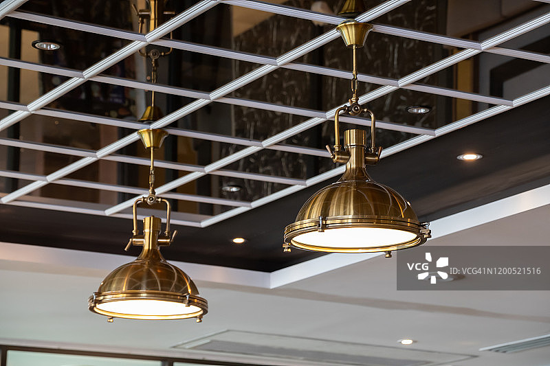 镜子天花板上的黄铜吊灯。金色吊灯装饰于餐厅。室内照明用金属灯。图片素材