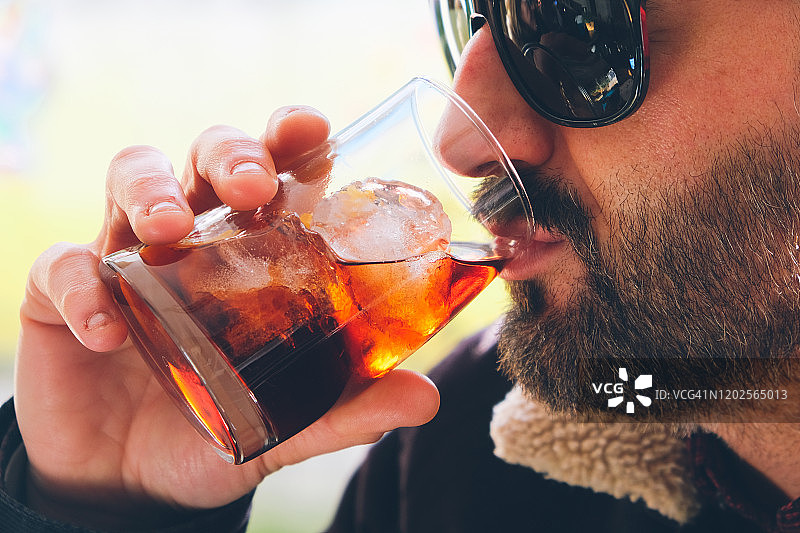 一个戴着太阳镜喝苦艾酒的中年男人的特写图片素材