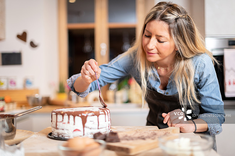 女人在家烘焙:装饰巧克力海绵蛋糕图片素材