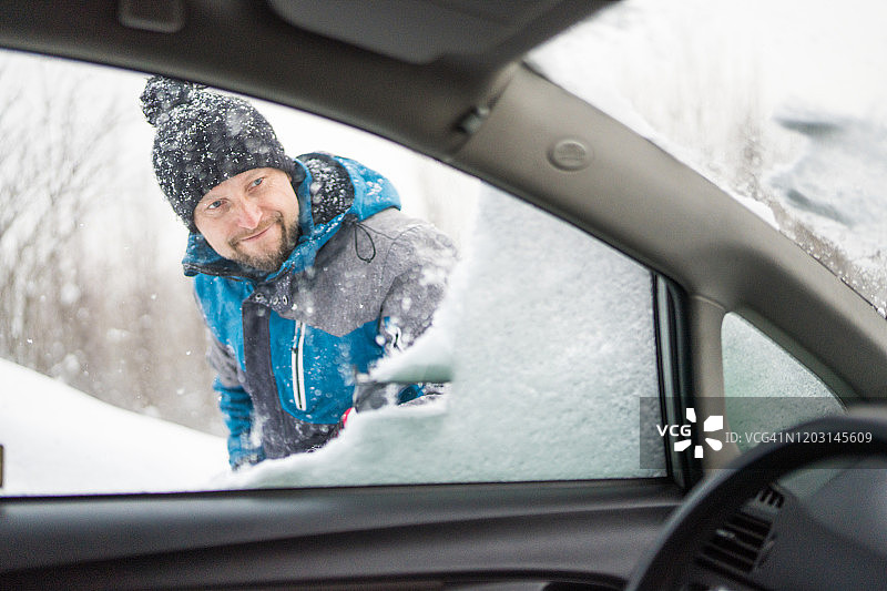 刮着车窗外的冰雪，男人正看着车窗外图片素材