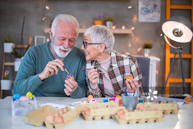漂亮的老年夫妇在装饰复活节彩蛋时玩得很开心。图片素材