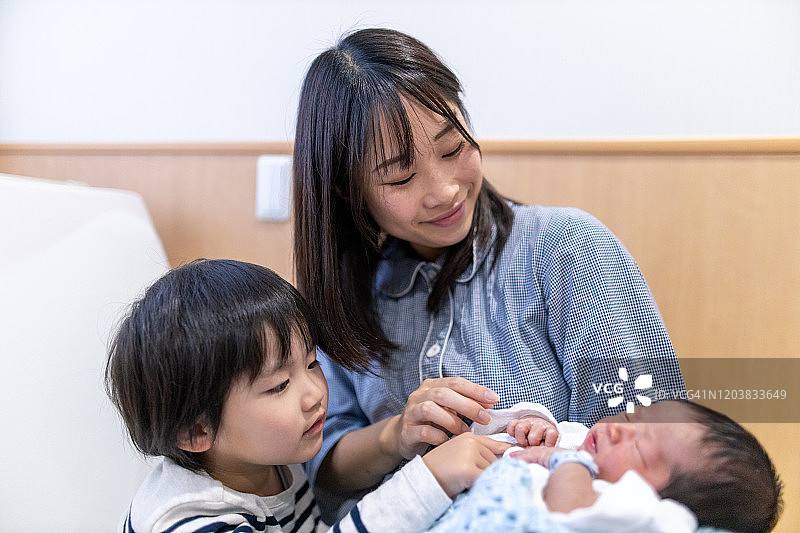 母亲和小儿子在医院看着他们的新生儿图片素材