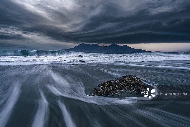 埃格岛戏剧性的冲浪与鲁姆岛在远处。苏格兰图片素材