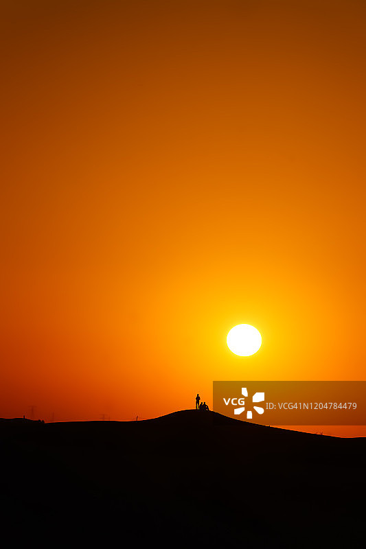 一群人的剪影站在迪拜沙漠日落图片素材