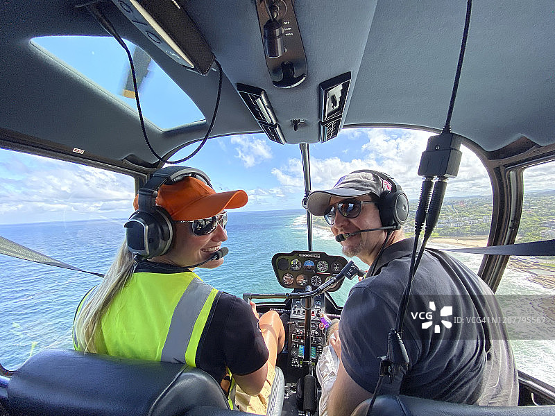 女性直升机和男性副驾驶驾驶直升机在海上飞行图片素材