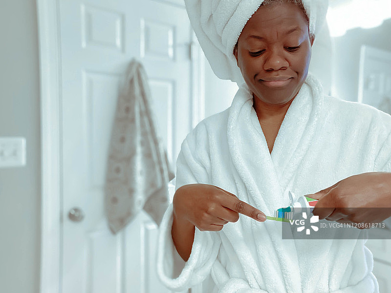 女人早上洗澡后把牙膏涂在牙刷上图片素材