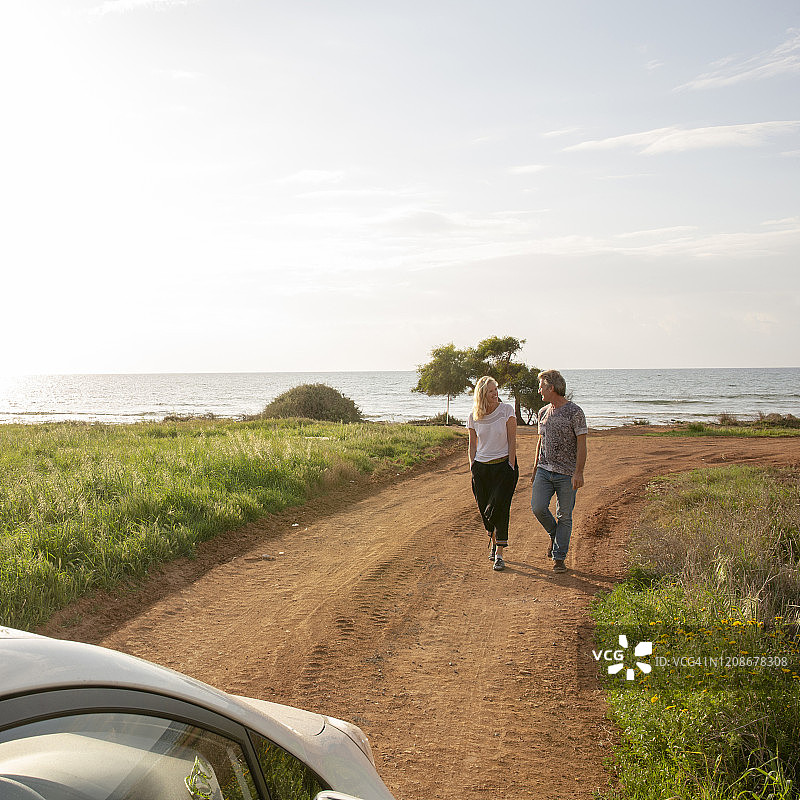 一对成熟的夫妇沿着乡间小路走向汽车图片素材