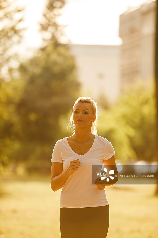 中年妇女喜欢在阳光灿烂的公园里跑步图片素材