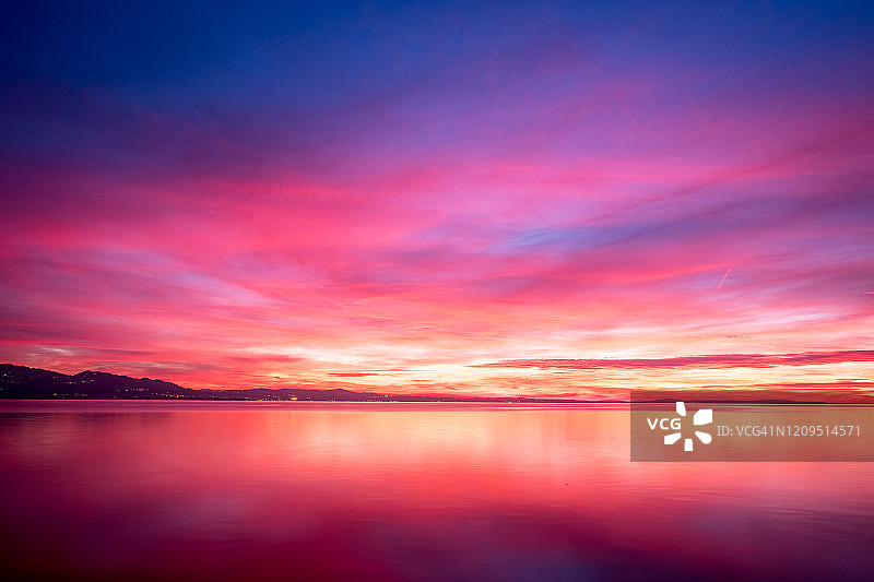 林道的波登西湖，在美妙的黄昏天空中，暗紫色的云与橙色的阳光和粉红色的光图片素材