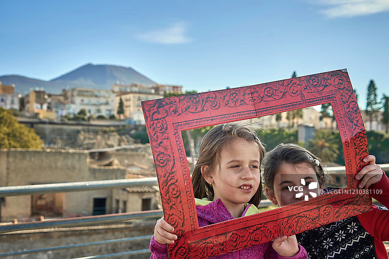 小女孩们用相框拍摄风景照片，意大利埃尔科兰火山口。图片素材