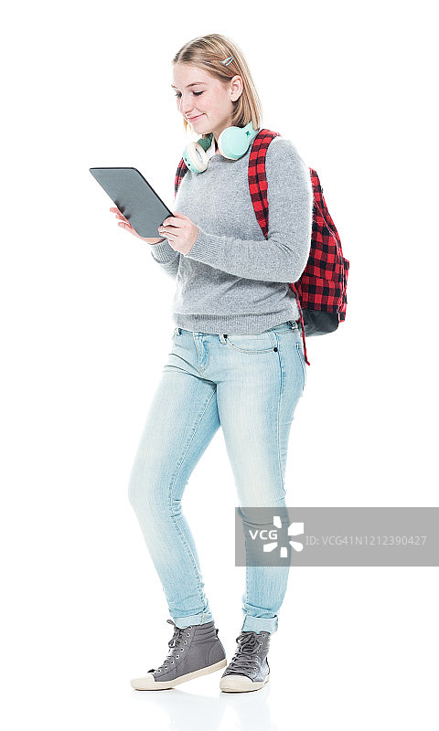 z一代女高中生穿着polo衫，拿着包，用着平板电脑站在白色背景前图片素材