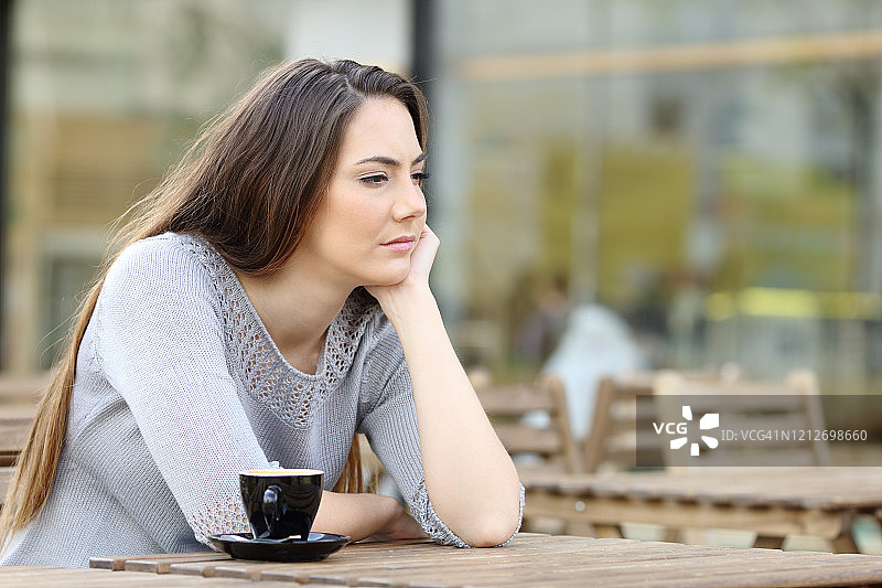 愁眉苦脸的女人望着别处的咖啡店图片素材