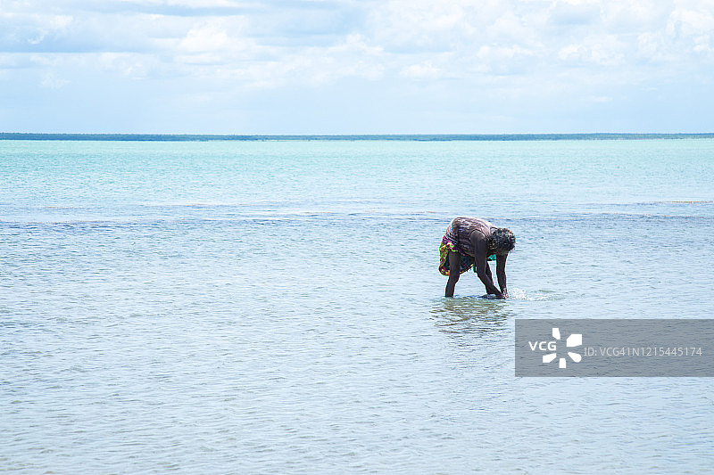 年长的土著土著妇女在浅水中弯腰寻找贻贝图片素材