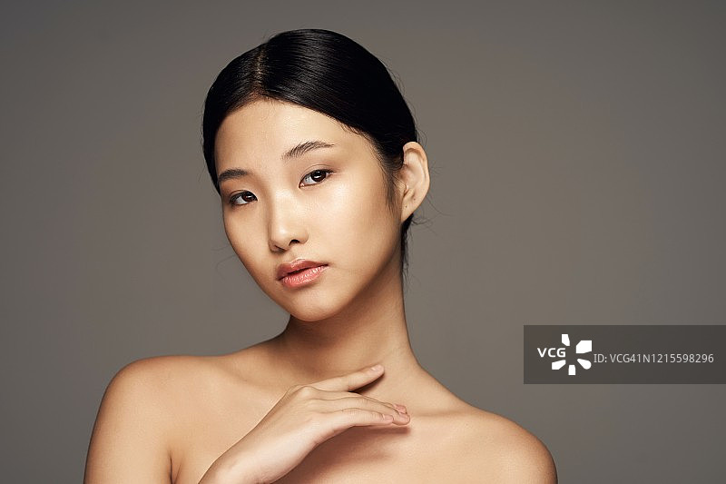 一个灰色背景的年轻亚洲女孩的干净和健康的皮肤。图片素材