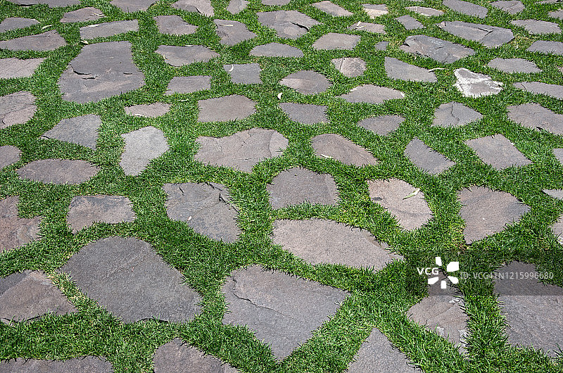 灰色的铺路石以一种“疯狂的铺路石”的模式穿过绿色的草坪图片素材