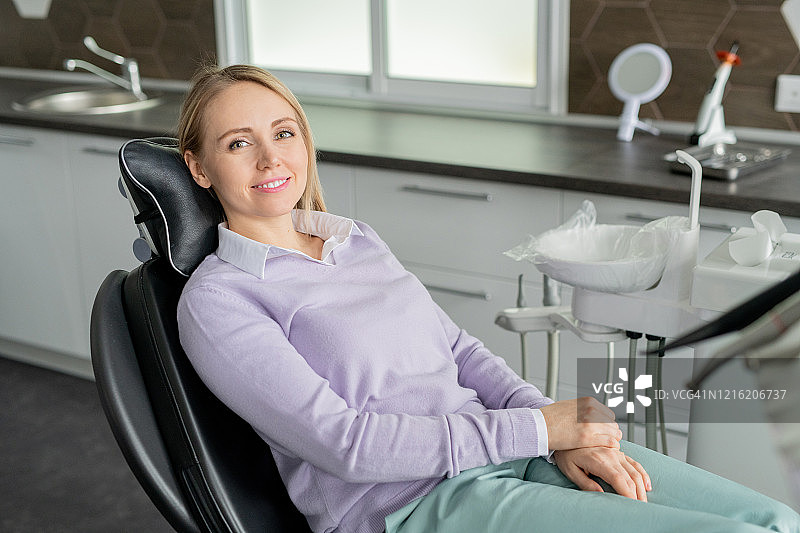 年轻貌美的当代牙科女病人坐在诊所微笑图片素材