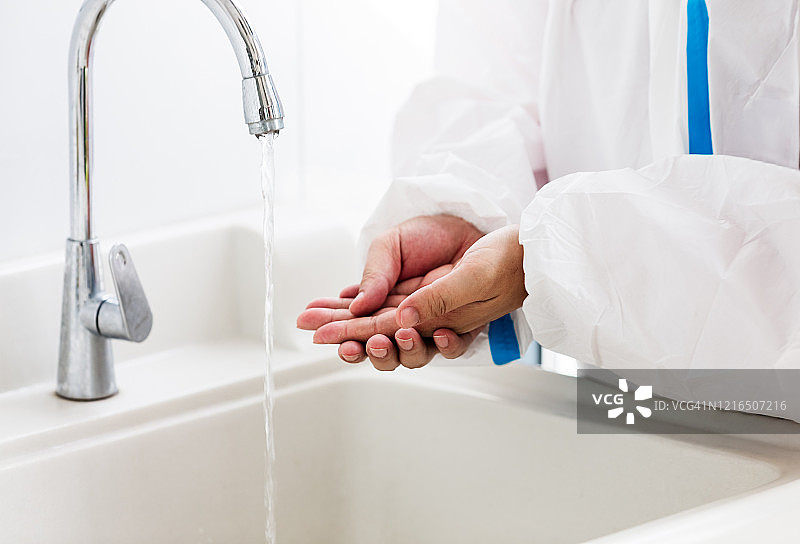 一个医生在防护服洗他的手的特写。图片素材