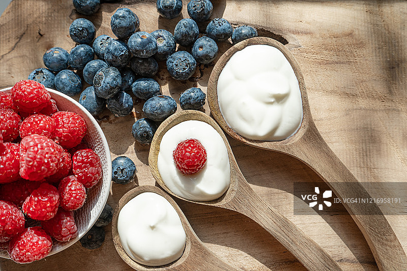 酸奶在碗和勺子，健康的早餐与新鲜的希腊酸奶，麦片和浆果的背景图片素材